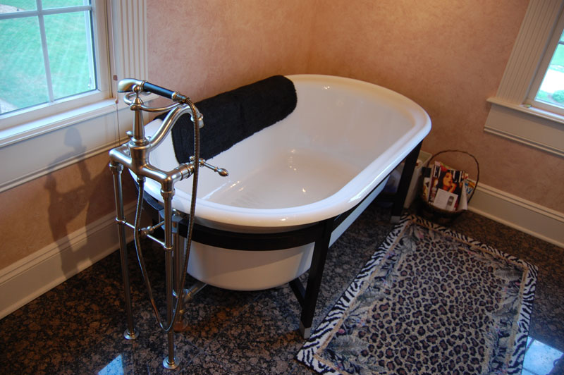 Standalone curved tub with raised silver faucetry.