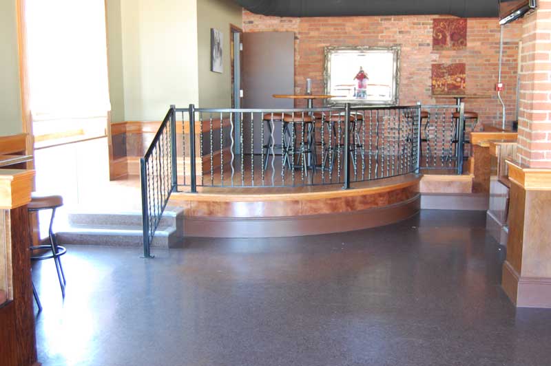Curved wooden platform with ornate metal fencing.